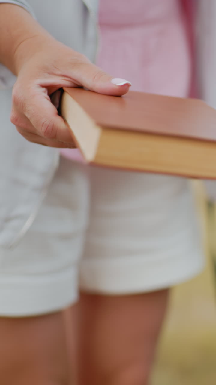 primer plano de una mujer entregando un libro a alguien con un perro de pie detrás, rodeado de vastas tierras de cultivo y balas de heno, perfecto para capturar momentos de ocio al aire libre