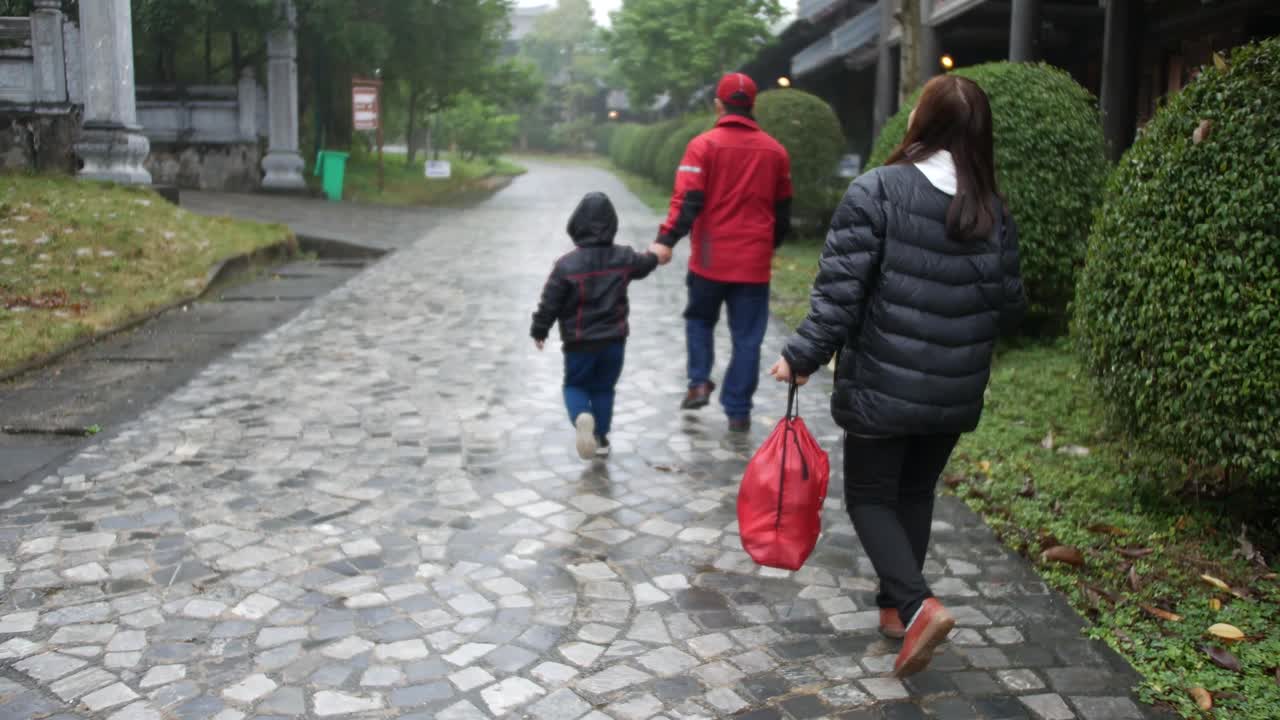 Vietnamese Family Walking On The Tiled Walkway In Tam Coc, Vietnam On A Cold Weather - dolly shot (forward)