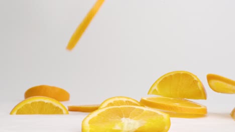 Bright-orange-citrus-slices-bouncing-on-white-table-top-in-slow-motion