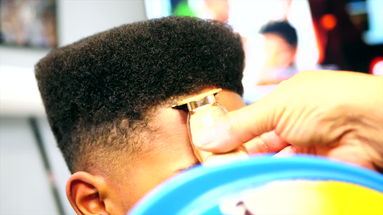 primer plano estático de peluquero haciendo corte de pelo en línea en el niño negro