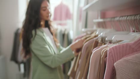 close-up of female hands plucked hanger choosing clothes in a clothing store. brunette woman hand runs across a rack of clothes buying clothes in a shopping mall. sale promotion and shopping concept