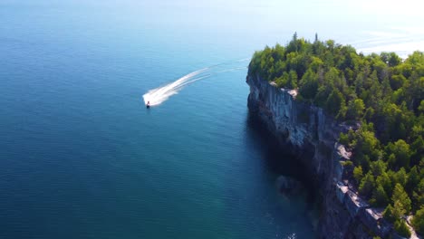 Rocky-Cliffs-Revealed-Person-Riding-Jet-Ski-In-Georgian-Bay,-Ontario-Canada