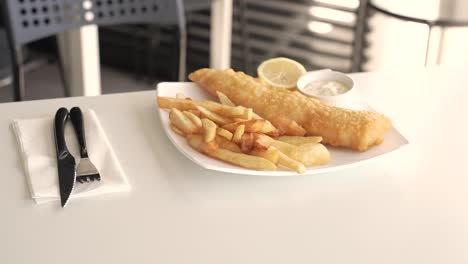 enjoying a delicious fish and chips meal in a cozy eatery during a sunny afternoon
