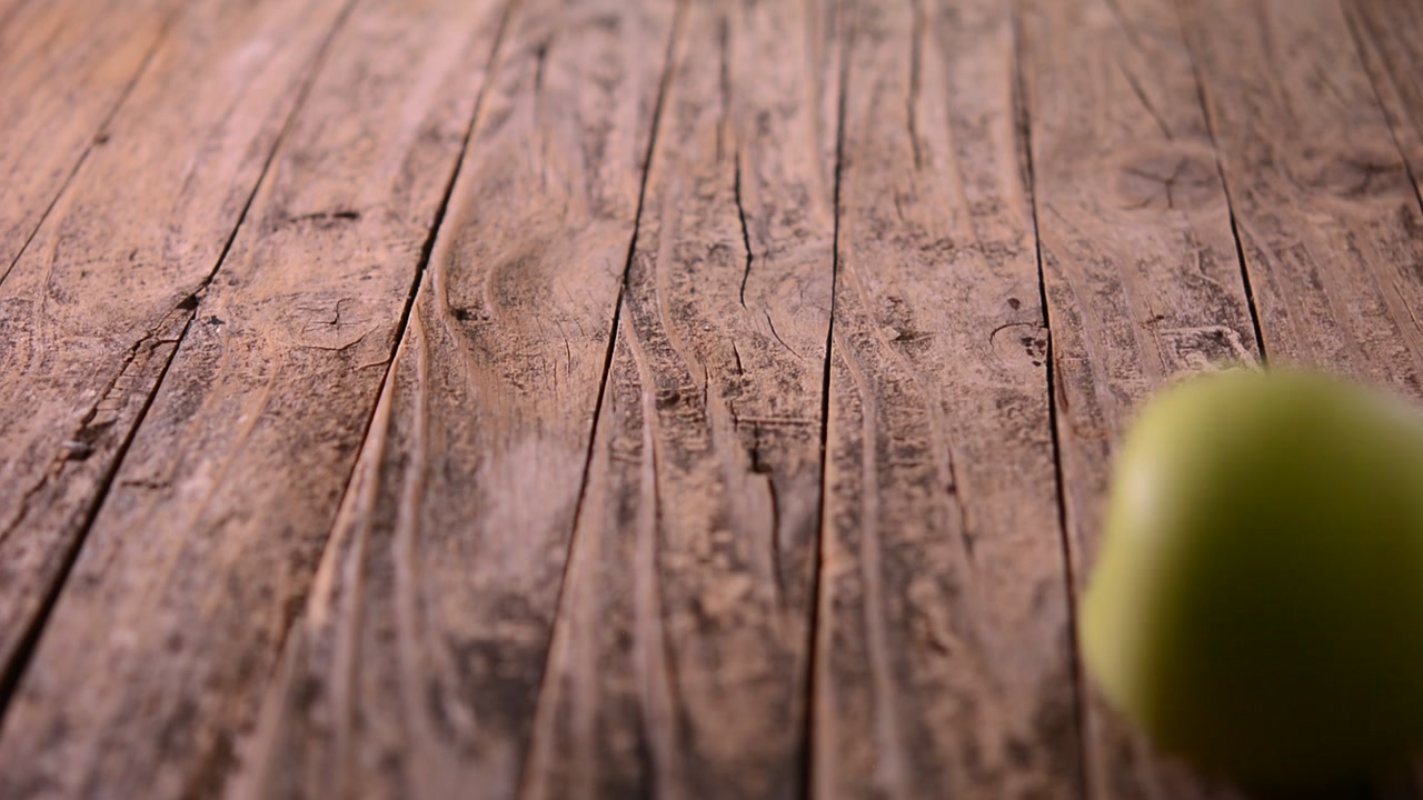 Mela verde che rotola su un tavolo di legno rustico