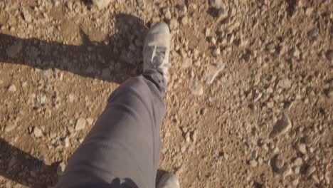 top view on feet with hiking boots walking on desert ground