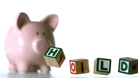 alphabet blocks spelling sold dropping down beside a piggy bank