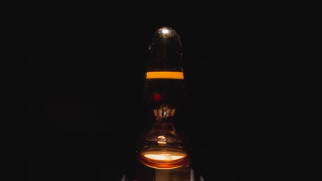 ampolla de vidrio con líquido marrón que refleja la luz del estudio