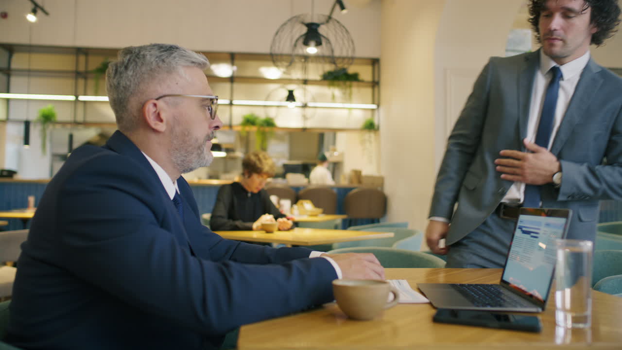 Two Business Partners Discussing Documents while Meeting at Restaurant