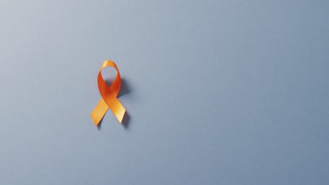 Video-of-orange-kidney-cancer-or-leukemia-ribbon-on-pale-blue-background