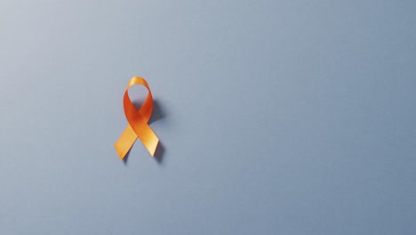 video of orange kidney cancer or leukemia ribbon on pale blue background