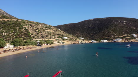 Aerial-shot-of-a-small-cycladic-beach,-with-some-pedal-boats-in-the-foreground