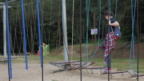 una turista divirtiéndose en el puente colgante en el parque kazubski gigantow en polonia - ancho