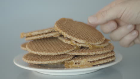 hand taking a single cookie from a pile of stroopwafels, a typical dutch treat