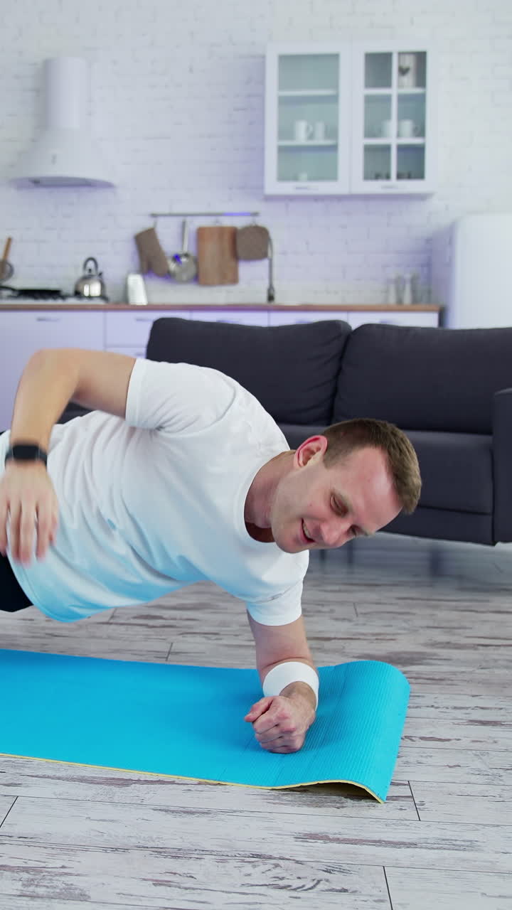 Fit man in t-shirt doing exervises. Healthy athletic man training in home. Vertical video