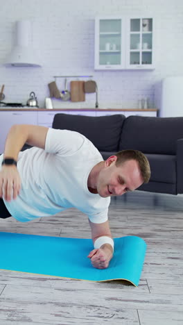 fit man in t-shirt doing exervises. healthy athletic man training in home. vertical video