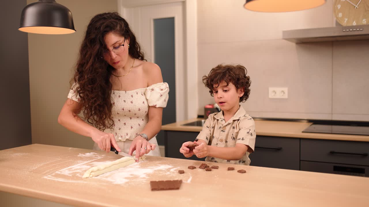 Mother and son baking cookies together in modern kitchen