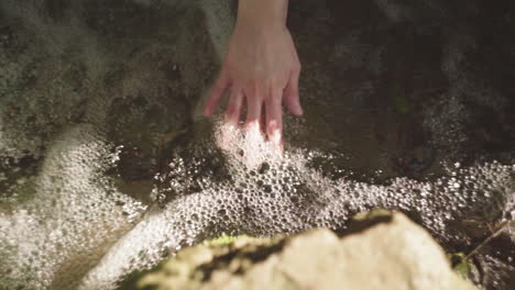 crop woman touching flowing water in river at night