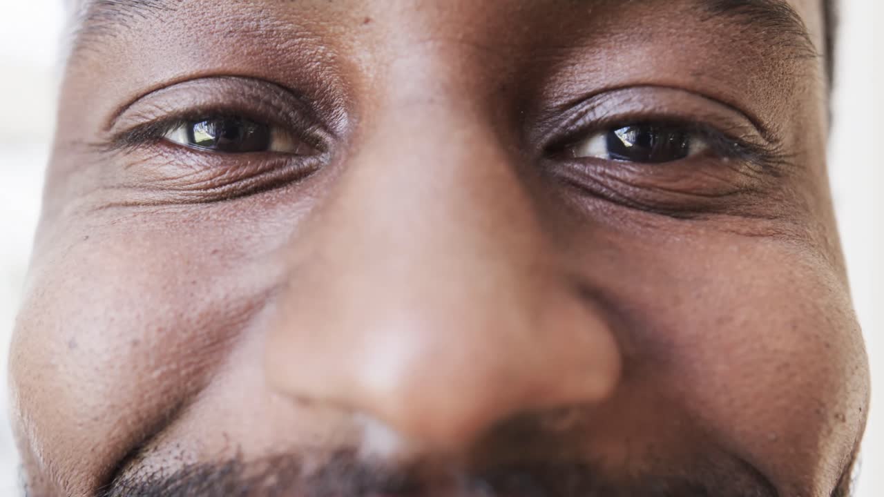 Portrait close up of eyes of happy african american man smiling, in slow motion, copy space