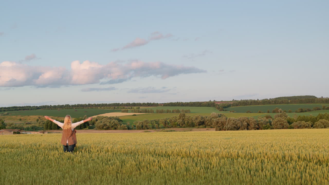 행복 한 여자 는 밀 들 과 함께 웅장 한 시골 풍경 을 즐기고 있다