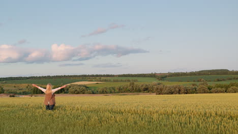 happy woman enjoying majestic rural landscape with wheat field