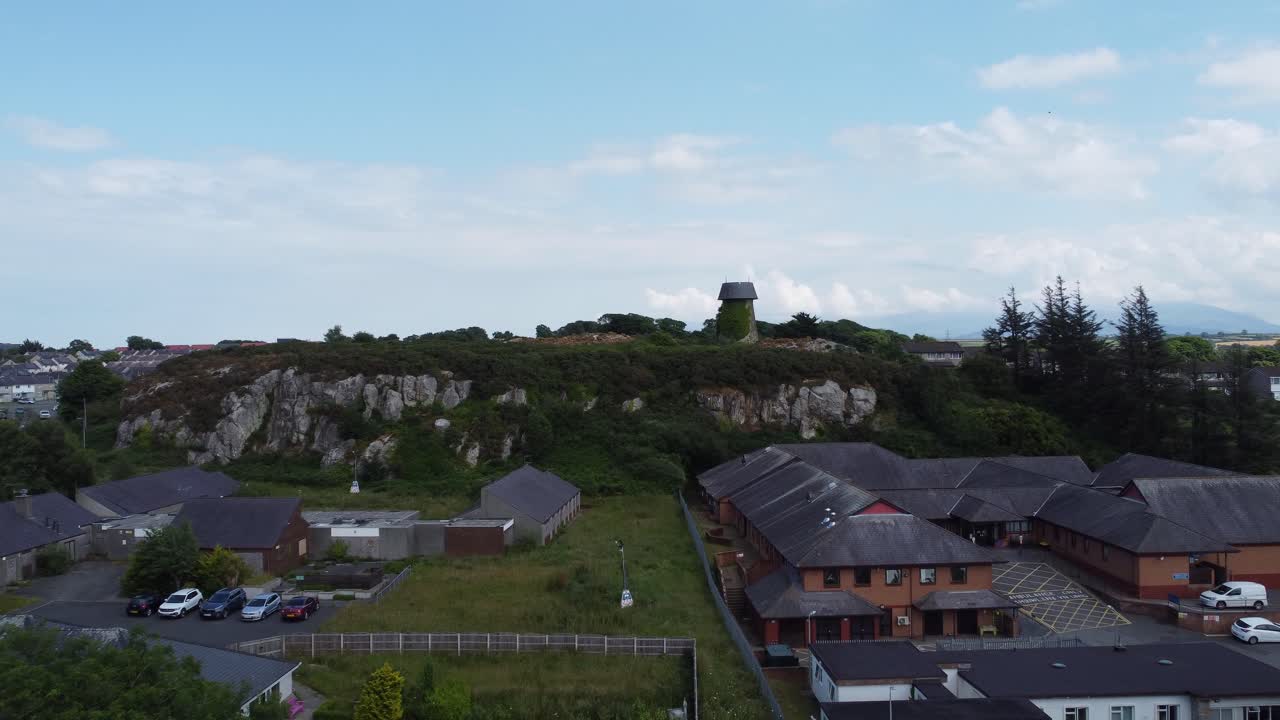 ветряная мельница илангефни, покрытая плющом, на склоне холма, воздушный вид, летящий над жилым массивом ангели.