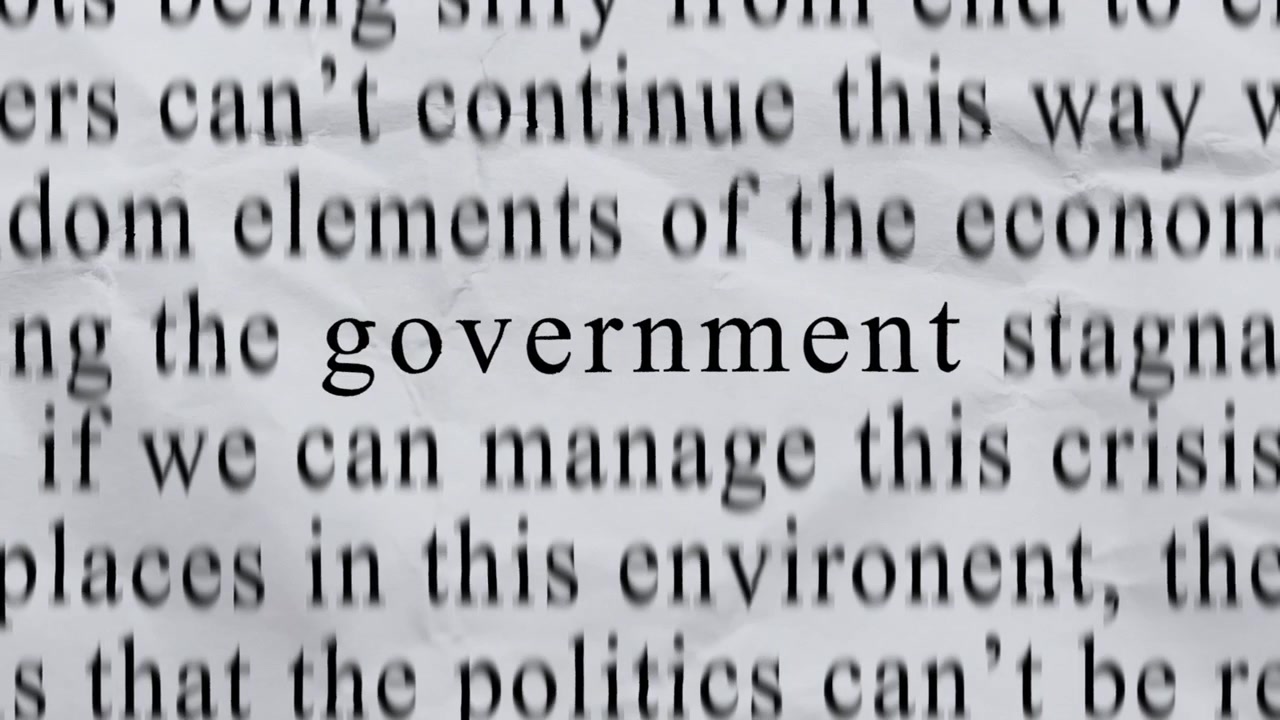 "GOVERNMENT"-teksti keskellä, korkeaenerginen ja nopea stop-motion-kirjoitus pyörii nopeasti rypistyneellä tekstuuripaperilla. Sanomalehtileike-tyylinen animaatio.