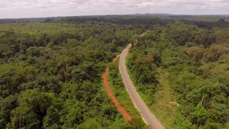 Aerial-drone-view-towards-a-rainforest-road,-in-the-Jungle,-on-a-sunny-day,-in-Nanga-Eboko,-Haute-Sanaga,-Southern-Cameroon