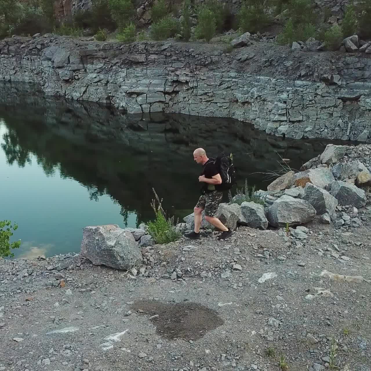 Aerial view of a tourist walks along the rocky shore of a lake. Traveler on the cliff. Camping season