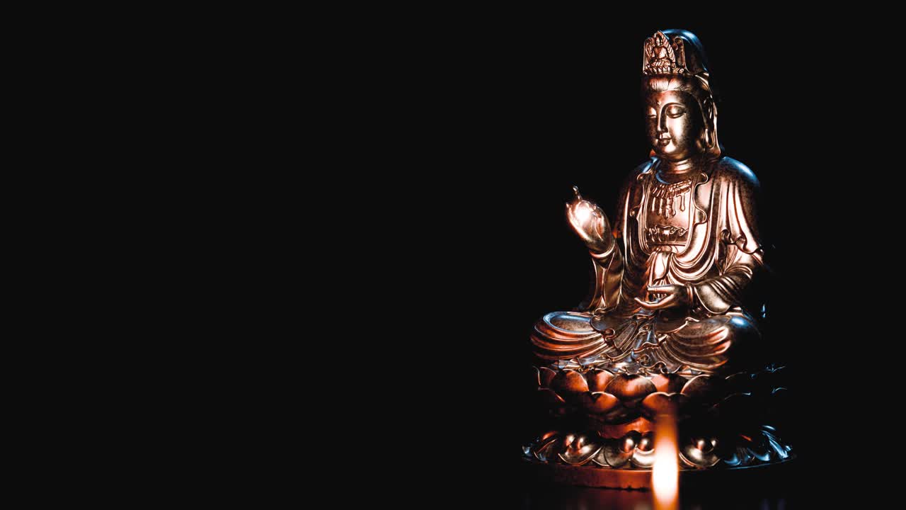 Statua dorata del Buddha Guanyin in rotazione con luce di candela.