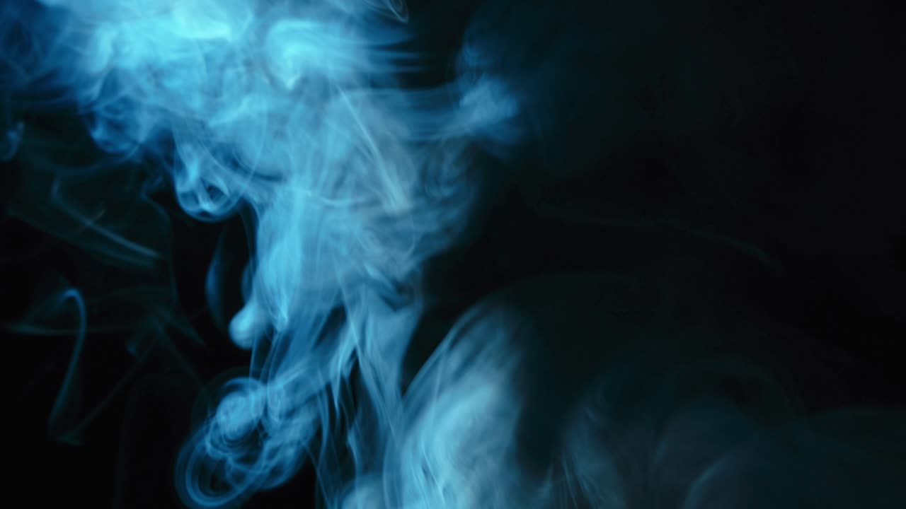 검은색 배경에 대해 느린 속도로 상승하는 파란색 연기에 여 있습니다.
