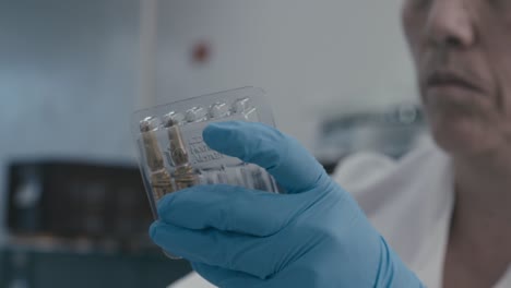 lab worker insert serum liquid into packing while working in medical drug production