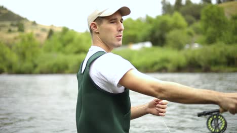 slow motion shot of a caucasian male fisherman casting his hook while fly fishing