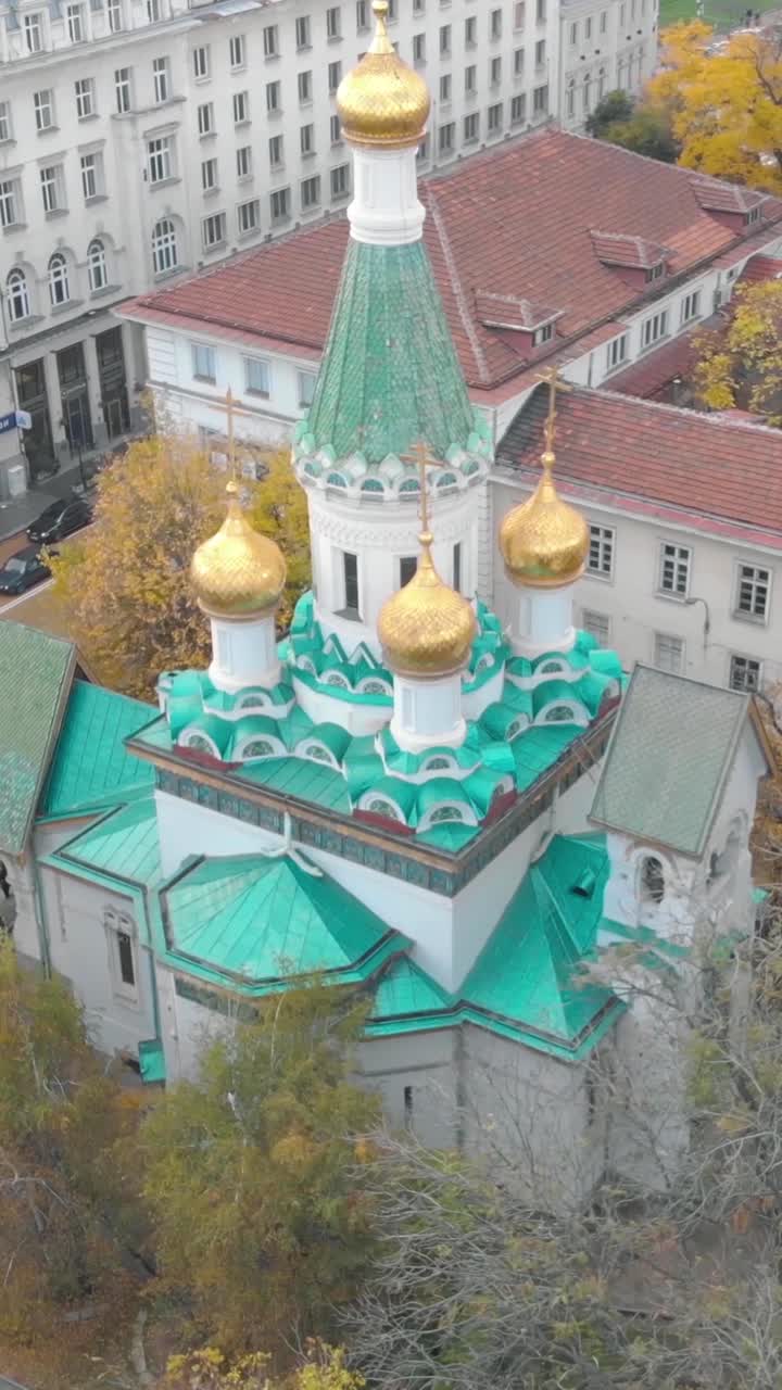 Aerial view of Saint Nikolas Russian Church in Sofia, Bulgaria, highlighting its iconic golden domes and turquoise green roof. Vertical Video