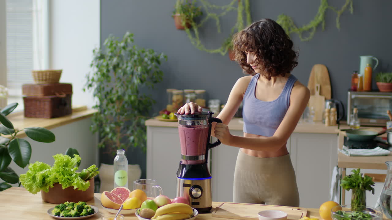 Ragazza in forma che usa un frullatore da cucina per preparare un frullato