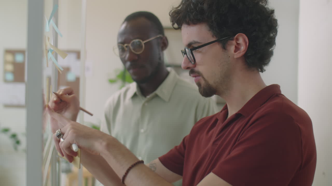 Multiethnic Colleagues Using Sticky Notes at Work in Office