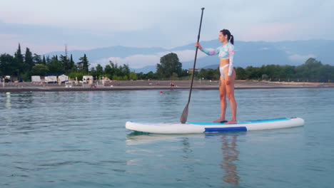 mujer haciendo paddleboard en un cuerpo de agua tranquilo