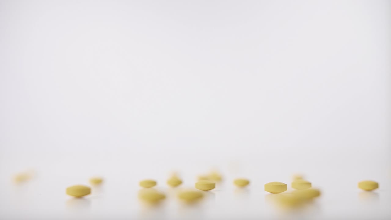 pastillas amarillas cayendo sobre fondo blanco en cámara lenta