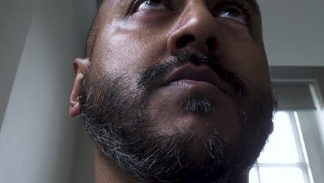 a cropped close up shot of the face and facial hair of an asian office employee sitting and working in front of his computer