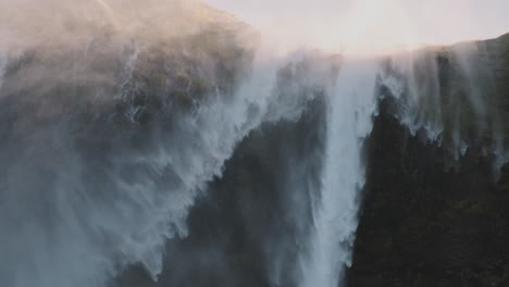 Mist-blows-over-top-of-cliff,-close-up-of-Iceland-reverse-waterfall