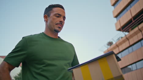 mail man crossing city closeup. serious courier guy checking mobile phone alone