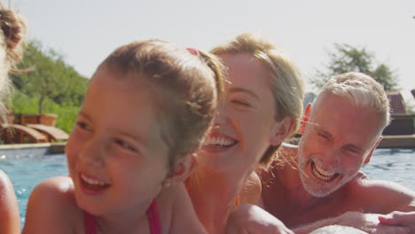 Familia-Sonriente-De-Varias-Generaciones-En-Vacaciones-De-Verano-Relajándose-En-La-Piscina-En-Una-Cama-De-Aire