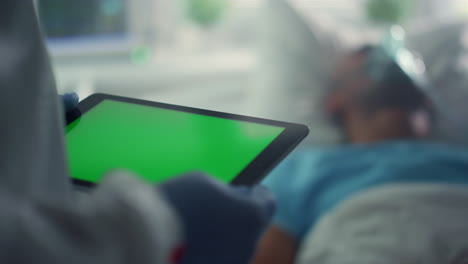 doctor using pad chroma key screen closeup. patient oxygen mask in hospital bed