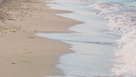 Strahlender-Sonnenaufgang-Am-Strand-Mit-Wellen,-Die-Mit-Morgensonne-Auf-Den-Sand-Spritzen