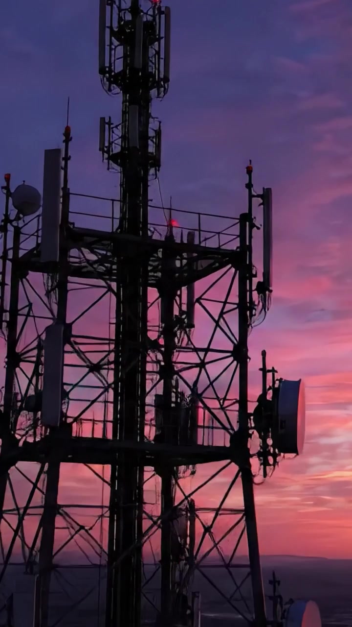Splendide vedute crepuscolari di una torre di comunicazione immersa nelle vibranti sfumature del tramonto, che illumina il cielo con un affascinante spettacolo di luci e colori infuocati.