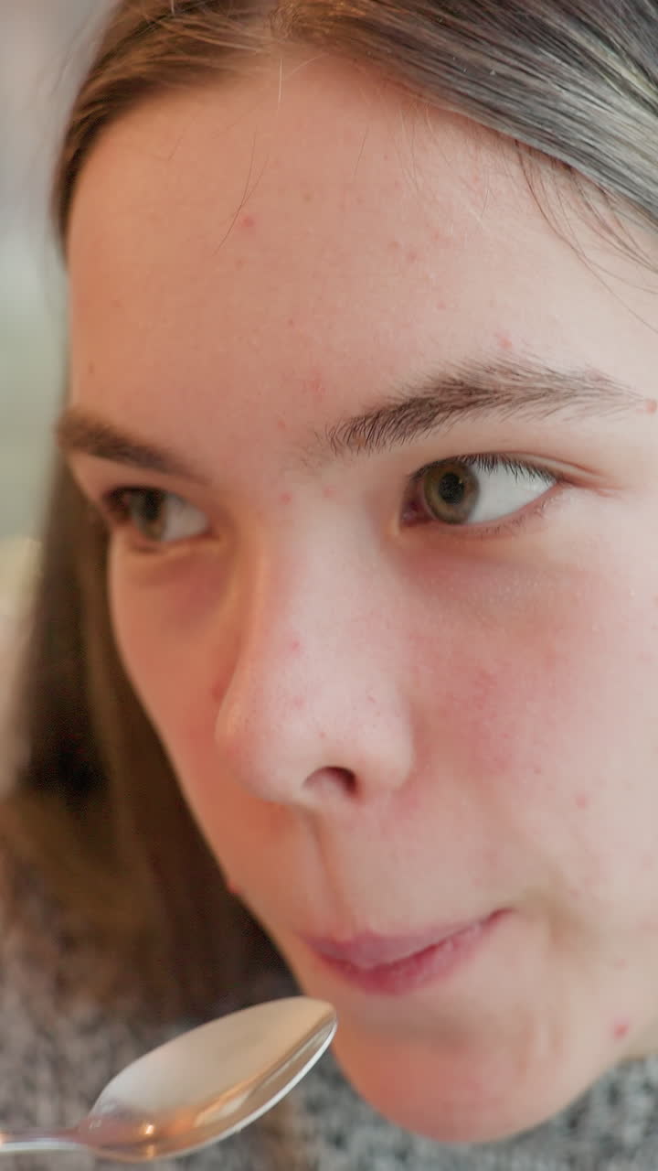 맛을 평가하면서 숟가락에 담긴 크림을 핥는 십 대 백인 소녀, 미묘한 생각에 잠긴 채 혀와 입술을 클로즈업하여 표현, 식도락가 및 평론가 분위기로 집에서 시식하는 모습, 텍스처 테스트