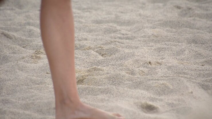 Woman walking on fine sand beach volleyball game cup