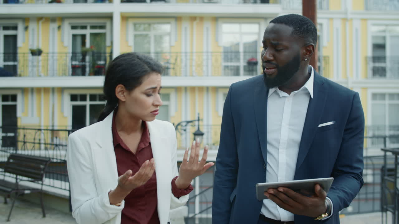 Frustrated multiethnic partners discussing project outdoors