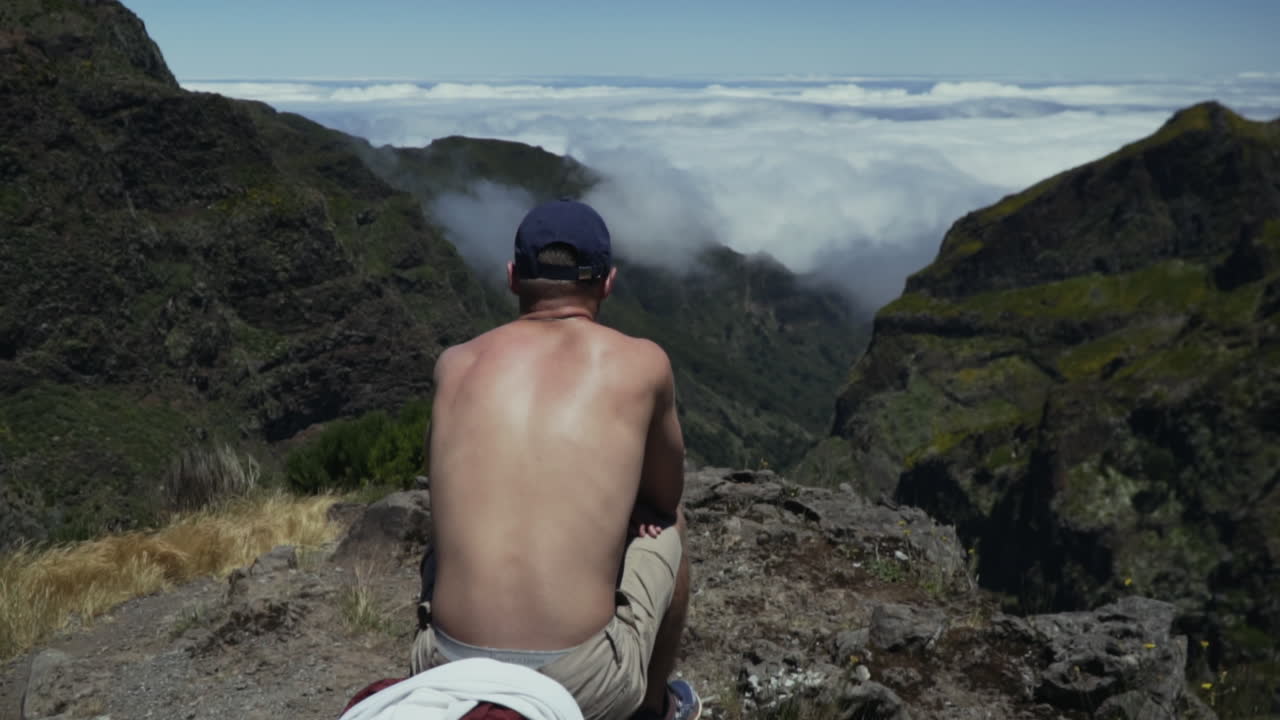 el joven se sienta en el mirador y disfruta de una vista espectacular del valle cubierto de nubes