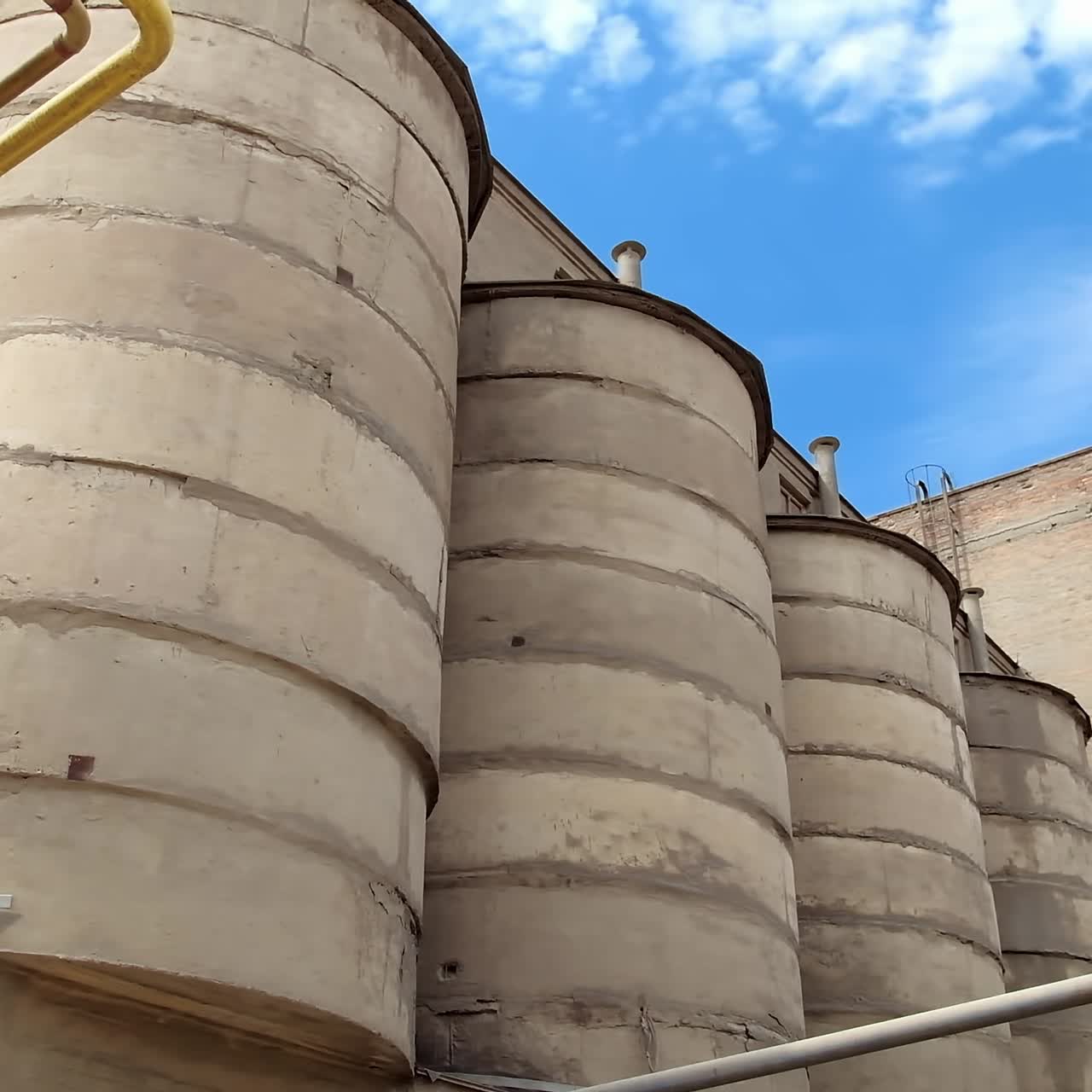 Huge industrial reservoir towers. Wide shot of cement storage on concrete factory. Exterior of industrial manufacturing. Close-up.