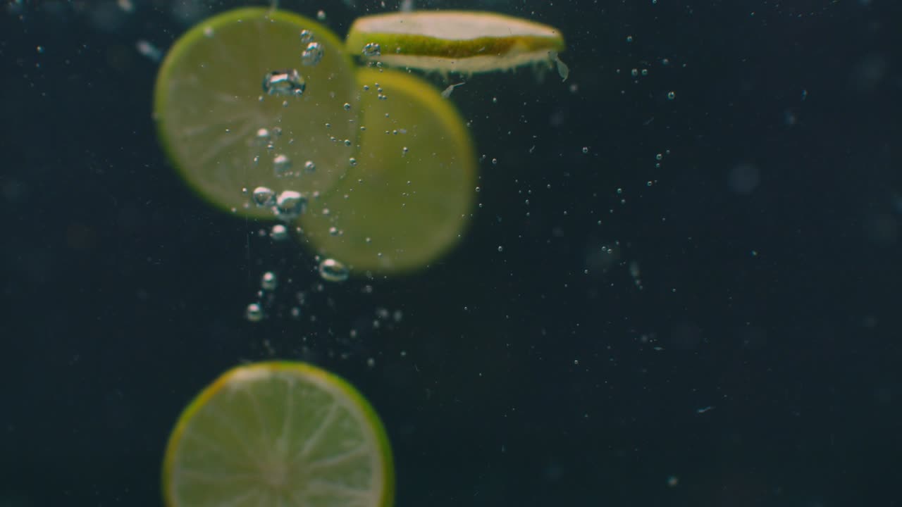 anillos de cal bajo el agua con burbujas de aire y en cámara lenta. fresco y jugoso vegetariano saludable.